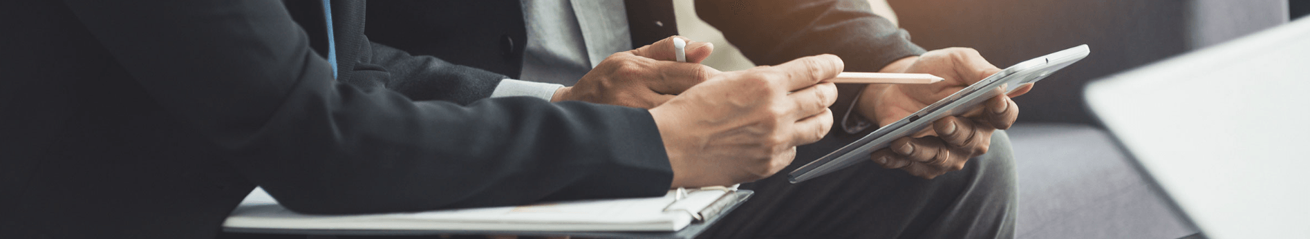 Close-up of hands writing notes and holding up a tablet.